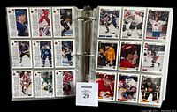 Binder pages with multiple hockey cards in protective sleeves, visible card backs and fronts, variety of players and teams in colorful uniforms.