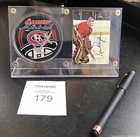 Overview of autographed puck and hockey card in acrylic stand with lot tag and pen