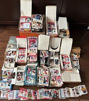 Multiple open boxes filled with hockey cards from various years, showing organized stacks and cards partially spread out across the floor.