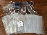 Large assortment of clear plastic card sleeves and holders with visible Ultra Pro branding and package labels, spread on wooden floor.