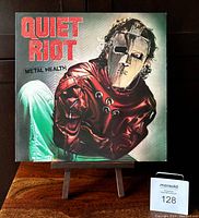 Front cover of Quiet Riot Metal Health vinyl album featuring iconic masked figure in a red straitjacket.