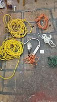Top-down image showing all extension cords, power bar and trouble light arranged on floor.