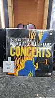 Cover of The 25th Anniversary Rock & Roll Hall of Fame Concert featuring colorful flames, text, and concert info.