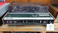 Front view of Panasonic turntable and cassette player with wood side panels and plastic dust cover showing control buttons and knobs