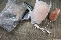 Three Himalayan salt crystal lamps of varying sizes wrapped in bubble wrap, with cords and bulbs visible.
