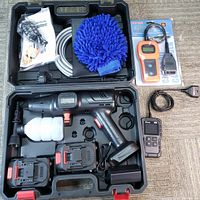 Top view of cordless high pressure washer kit in carrying case with foam cannon attachment, two batteries, charger, hose, microfiber mitt, and manual.
