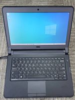 Opened laptop powered on showing keyboard, palm rest and display with Windows desktop