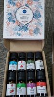 Opened box showing 8 essential oil bottles with labels: Camphor, Raspberry, Pine Needles, Coconut, Strawberry, Cypress, Thyme, Grapefruit.