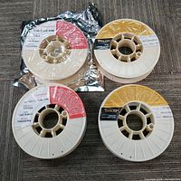 Overview of four wire spools on carpet, one sealed in foil.
