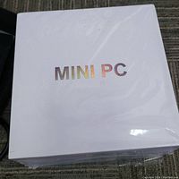 White sealed box labeled 'MINI PC' in holographic text