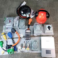 Wide shot of entire lot showing all electrical components, safety helmet with earmuffs, and distribution unit on carpeted floor.