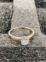 Front view of ring on black surface showing diamond and band curvature.