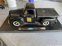 Front-side angle of black 1948 Ford F-1 die-cast pickup displaying detailed body and base.
