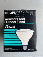 Box front showing Philips branding, product type as Weather-Proof Outdoor Flood 75 Watt, illustration of bulb, 130 volts and standard base info
