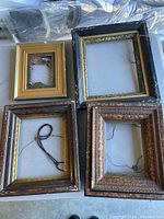 Top-down view of all four assorted vintage wooden picture frames arranged on a surface. Each frame varies in size and design with visible vintage characteristics.