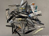 Overview of assorted safety razors and straight razors spread out on a surface, showing varied handle types and colors.