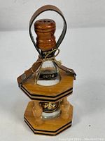Front angle view showing the Ouzo bottle in the wooden stand with leather handle and stopper detail.