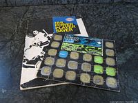 Soft cover NHL Power Player Saver book with black and white hockey player cover and fully completed stickers, and Sunoco Olympic Game collector page with many metal medal sections.