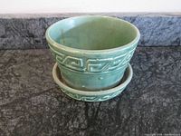 Front view of green McCoy ceramic planter showing Greek key decorative pattern and matching underplate, placed on dark countertop.