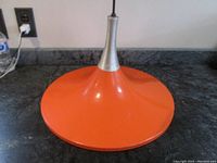 Full view of the orange enamel witch hat pendant light with metal topper and wire.