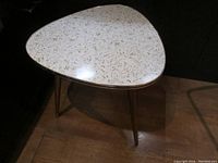 Full view of triangular side table showing overall shape and legs