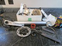 Photo showing various bike parts including Hope crankset, cassette, headset spacers, and tire box on countertop.