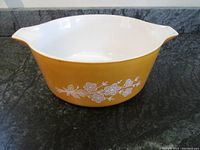 Full view of Pyrex mixing bowl, showing yellow-orange exterior and white interior with spouts on both sides.