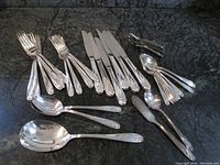 41 pieces of 1847 Rogers Bros cutlery displayed with knives, forks, spoons, and serving implements arranged on a dark surface.