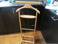 Full view of the vintage Italian wood clothes butler standing on the floor, showing wood frame, hanger, and tray.