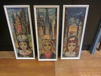 Three framed prints side by side showing big eyed girls with Parisian backgrounds