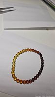 Photo of the gradient Baltic amber bracelet laid flat showing color transition from yellow to dark red.