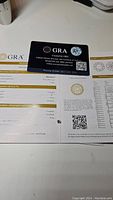 GRA moissanite certification card with warranty ID visible alongside grading report showing half carat 0.50 ct size, D color, VVS1 clarity, and round brilliant shape.