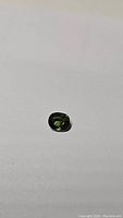 Front view of a small cushion-cut green sapphire gemstone showing its color, clarity, and polish.