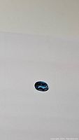 Oval cut London Blue Topaz gemstone on neutral background, showing color and cut details.