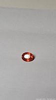 Oval cut mandarin orange sapphire gemstone on a plain background showing the gemstone's size, shape, and color.