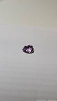 Photo of a single pear cut natural amethyst gemstone on a white background