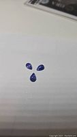 Three small pear-shaped purple-blue tanzanite cabochons arranged together on a flat surface, showing overall size and color.