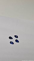 Four pear-shaped royal blue Kyanite gemstones on white background showing color and cut.