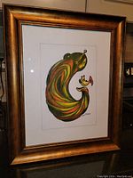 Photo of framed abstract acrylic painting on paper depicting mother and child shapes with earth tone colors in gold frame.