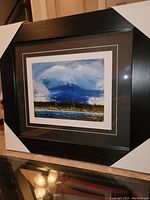 Framed fine art print in black frame with corner protectors.