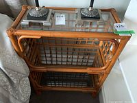 Top and front view showing the wooden woven frame with glass shelves and surface, with decorative lamps placed on top.