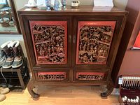 Front view of cabinet showing full carved red panels and curved legs