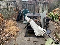 Overall view of all outdoor furniture items in a fenced garden area including chairs, umbrella, tables, and planter