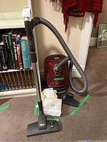 Full view of vacuum assembly with hose, wand, attachments, manual and bags