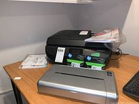 HP OfficeJet 4650 printer with two HP 63 XL ink cartridges and Canon iP100 printer on table.