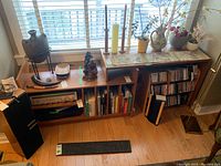 Both shelving unit pieces in place under window with various decorative items.