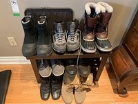 Photo showing multiple pairs of boots arranged on an Ikea shoe rack, highlighting styles and condition