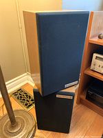 Pair of Audio Spec Review 80 speakers standing vertically with black fabric covers and wooden side panels visible.