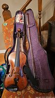 Violin and bow inside open hard case with purple interior lining