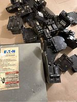 Over 20 single and multiple double pole black circuit breakers and a grey Eaton general duty safety switch with ON/OFF handle and warning labels visible.